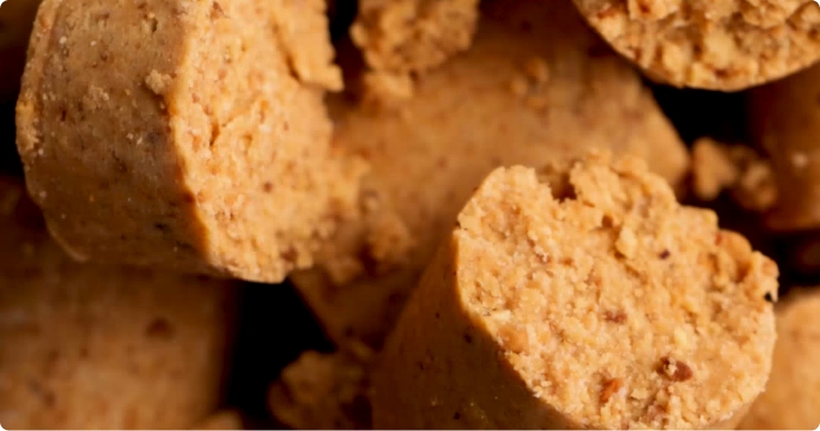 Close-up de pedaços de paçoca esfarelada, mostrando textura cremosa e granulada.