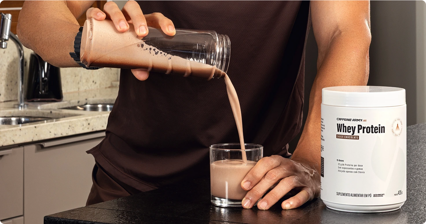 Pessoa servindo shake de Whey Protein sabor chocolate de um shaker para um copo, com pote do produto ao lado.