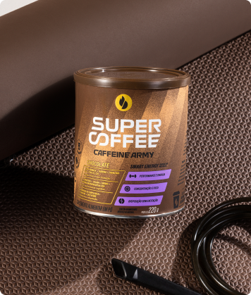 Lata SuperCoffee Chocolate 220g apoiada em tapete de treino marrom, ao lado de corda e acessórios fitness.