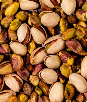 Close-up de pistaches abertos e inteiros em tons de verde e marrom.